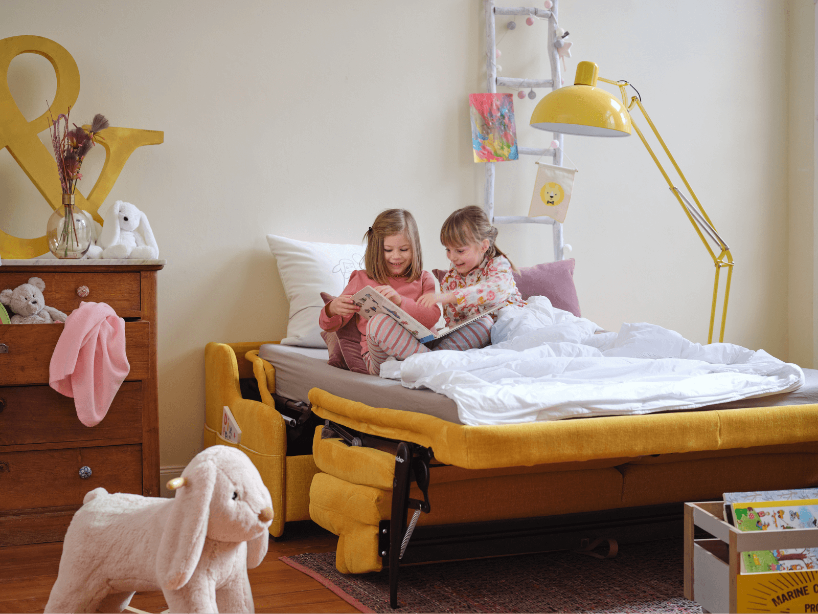 Kinder auf einem gelben geöffneten Schlafsofa am lesen